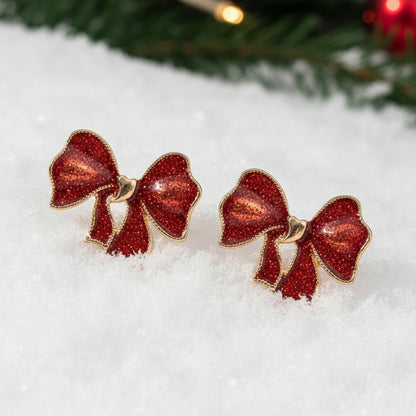 Crimson Glitter Bow Earrings on a snowy background