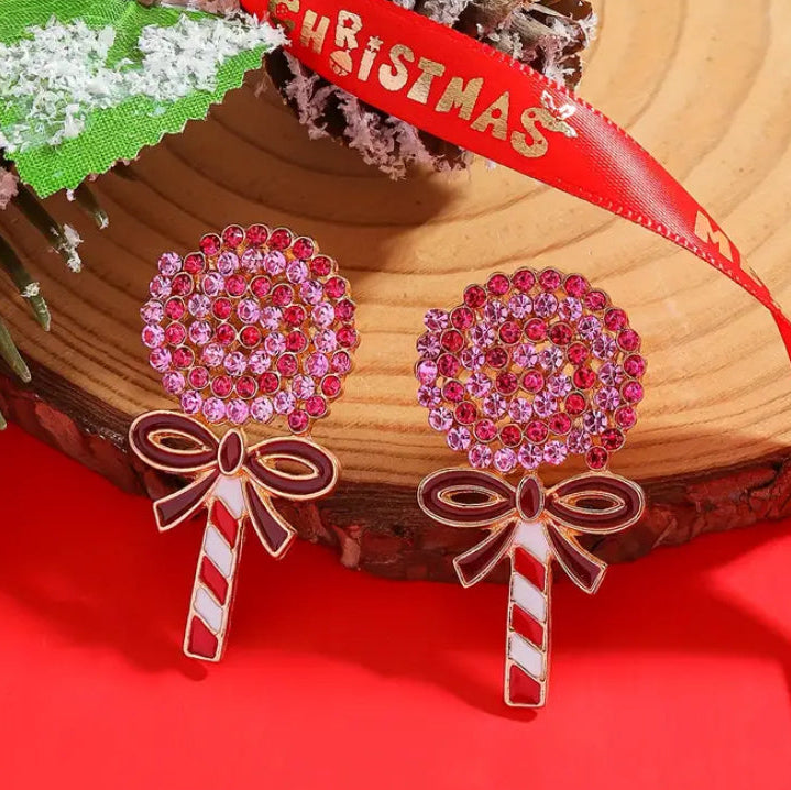 Oversized Holiday Candy Swirl Earrings with red and gold ribbons on a red background.