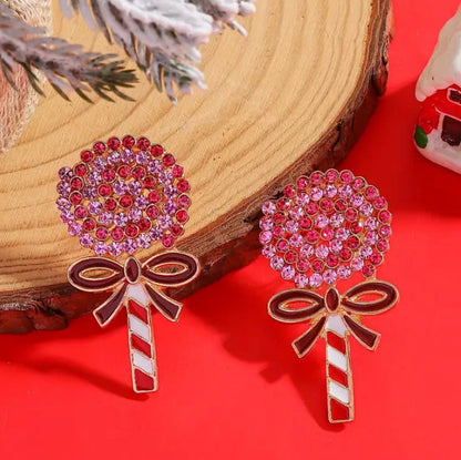 Oversized Holiday Candy Swirl Earrings with red and pink gemstones on a red surface.
