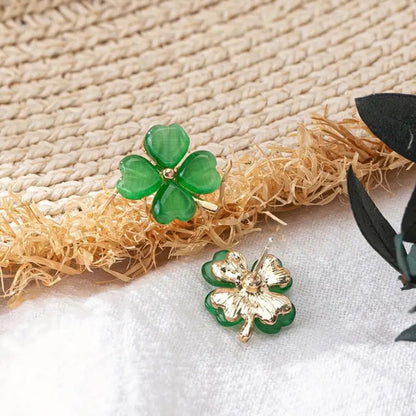 Gold and Green Four-Leaf Clover Shamrock Earrings on a textured surface