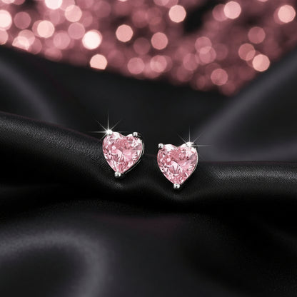 Heart-shaped pink earrings on a black fabric background