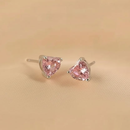 Pair of pink heart-shaped stud earrings on a beige background