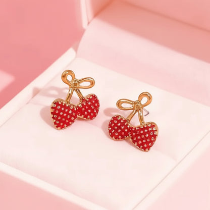 Gold Bow Strawberry Earrings on a pink surface