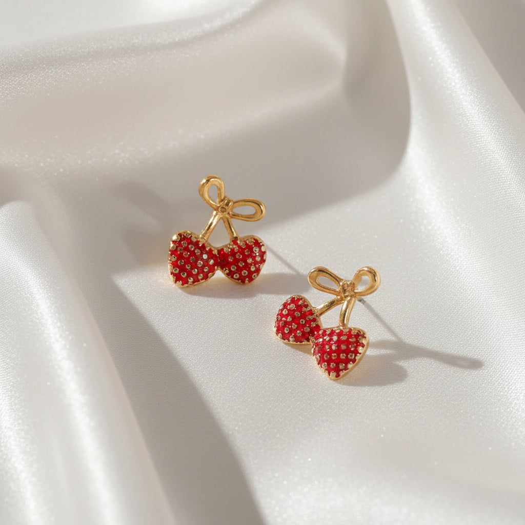 Gold Bow Strawberry Earrings on a white fabric background