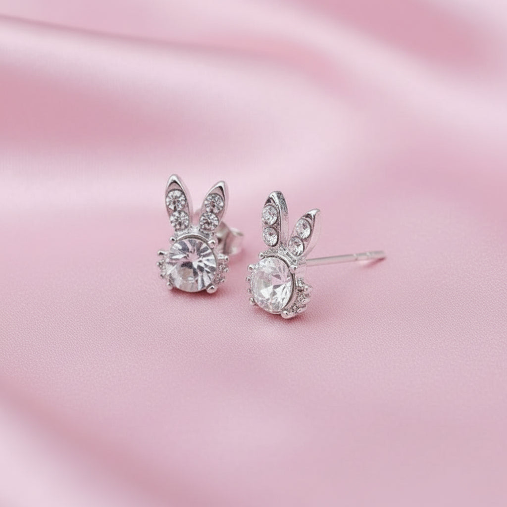 Sweet Bunny Sparkle Earrings with clear gemstones on a pink satin background