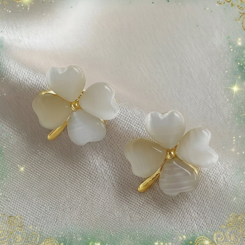 Opalescent Clover Earrings with gold accents on a light fabric background
