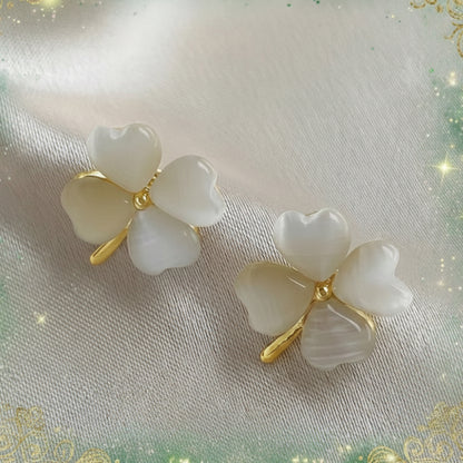 Opalescent Clover Earrings with gold accents on a light fabric background