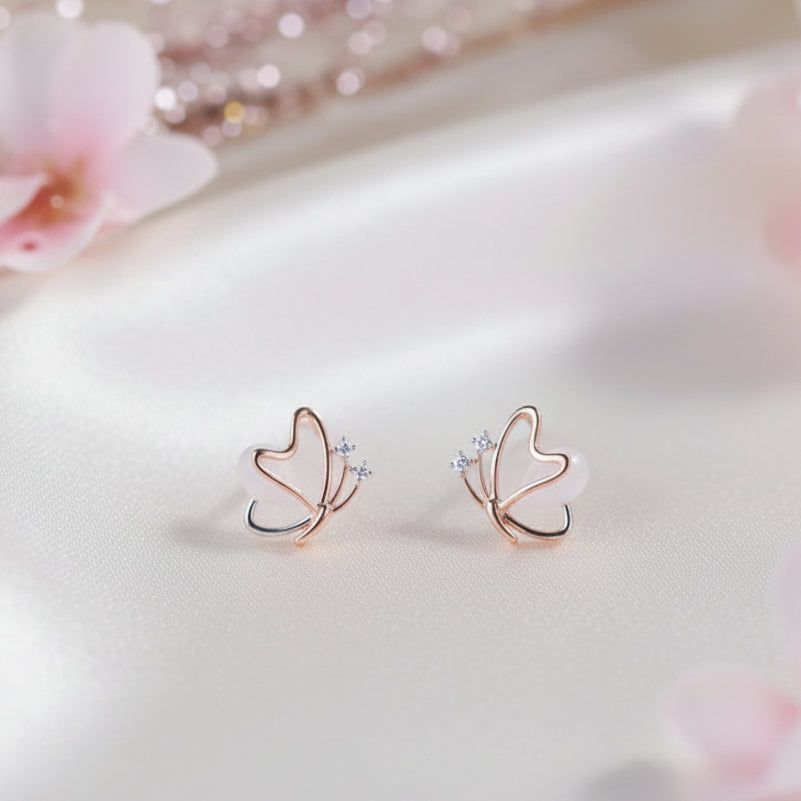 Rose Gold Butterfly Pearl Earrings on light fabric