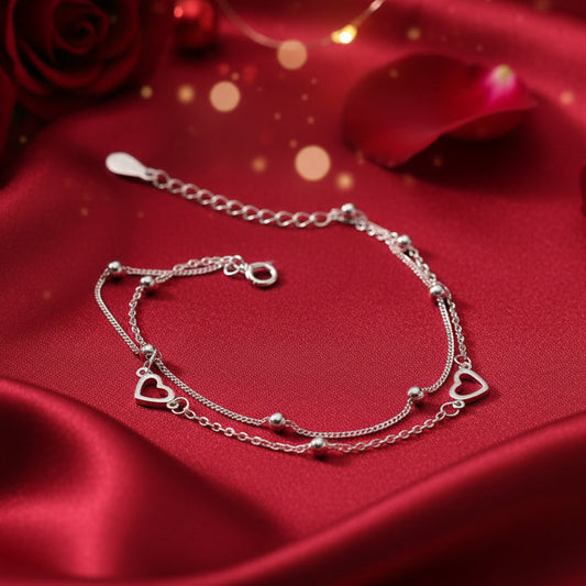 Silver anklet with heart-shaped charms on a red background