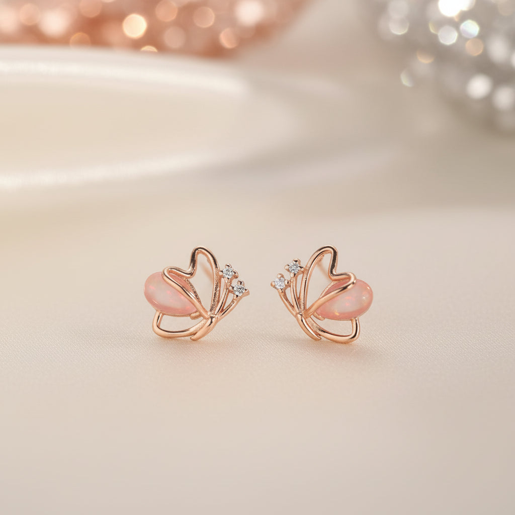 Rose Gold Butterfly Pearl Earrings with pink stones on a soft beige background