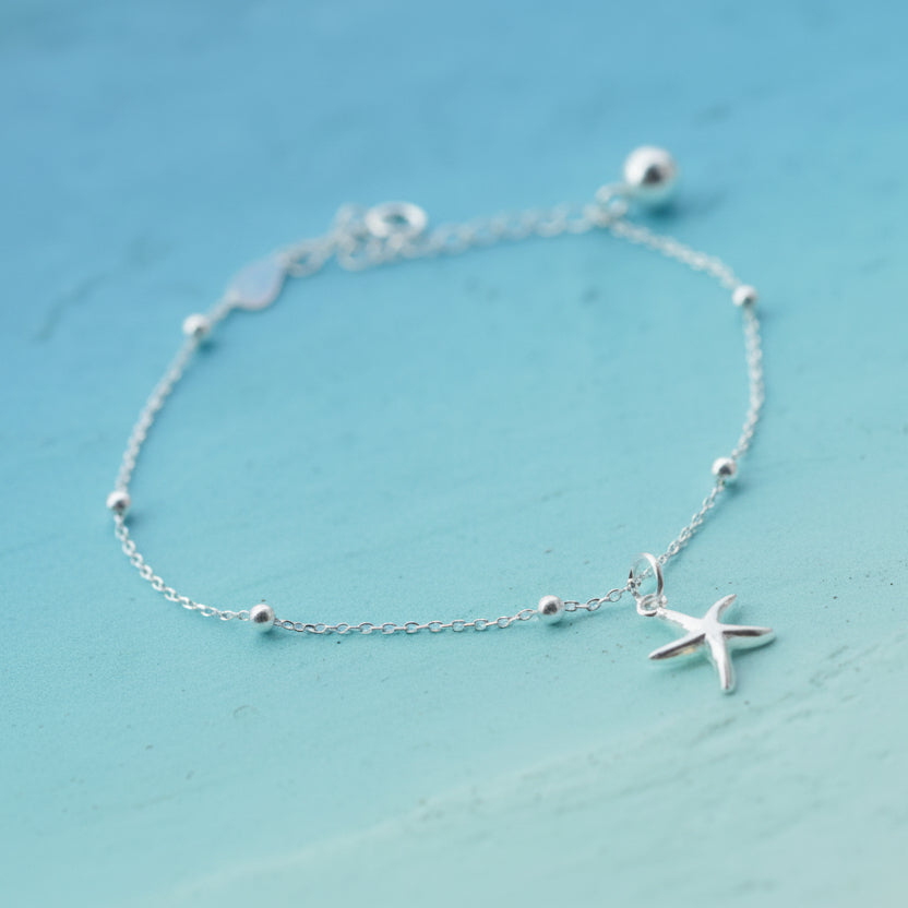 Silver Coastal Starfish Bead Bracelet with a starfish charm on a light blue background