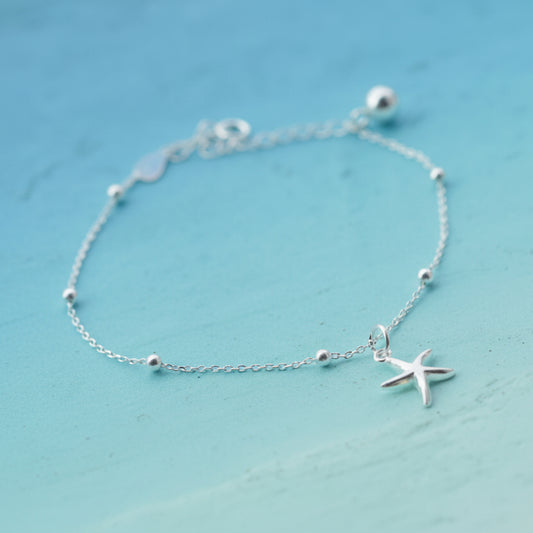 Silver Coastal Starfish Bead Bracelet with a starfish charm on a light blue background