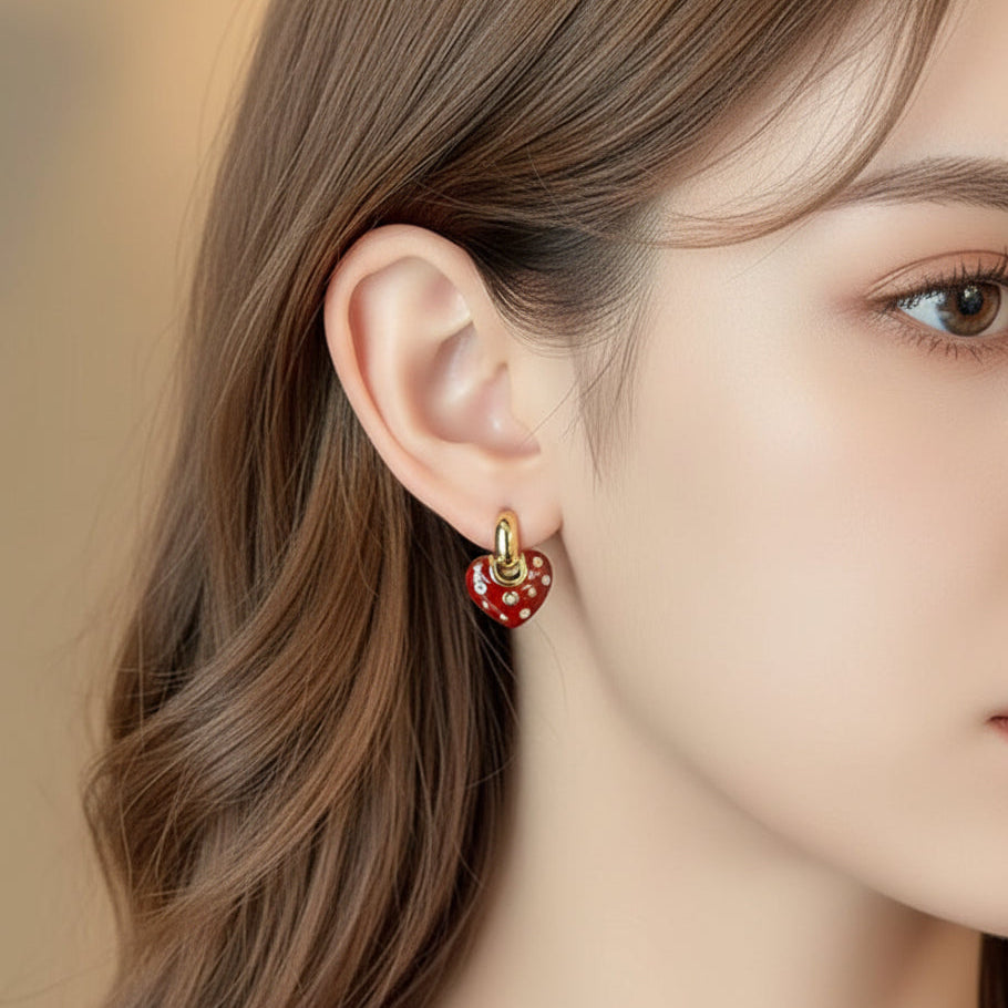Crystal Accent Red Heart Earrings with gold accents being worn by a person.