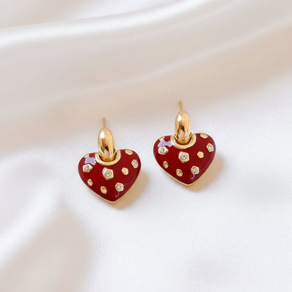 Crystal Accent Red Heart Earrings with red enamel and gold accents on a light fabric background