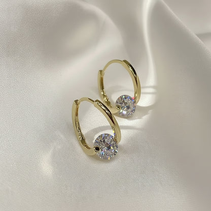 Gold Zircon Drop Hoop Earrings with clear gemstones on a light fabric background