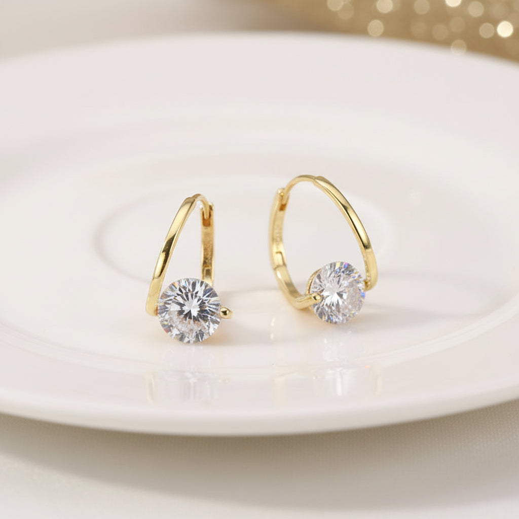 Gold Zircon Drop Hoop Earrings with clear gemstones on a black surface