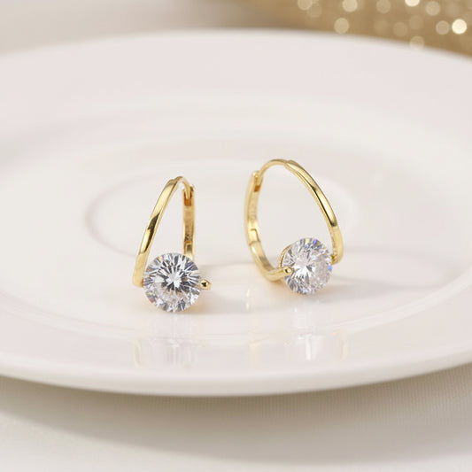 Gold Zircon Drop Hoop Earrings with clear gemstones on a black surface