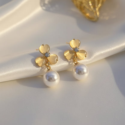 Luminous Gold Clover Pearl Drop Earrings on a white fabric