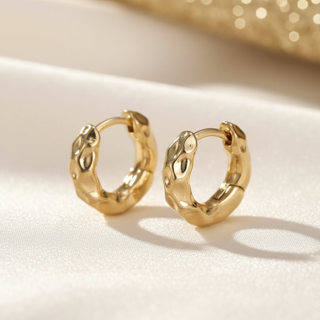 Textured Gold Hoop Earrings on a light beige surface with a soft background