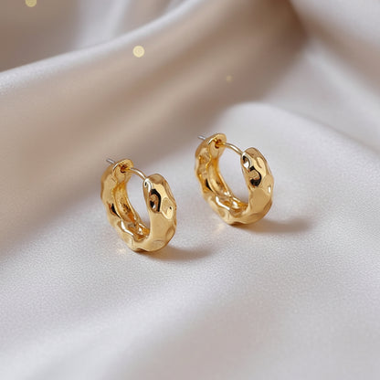 Textured Gold Hoop Earrings on a beige fabric background