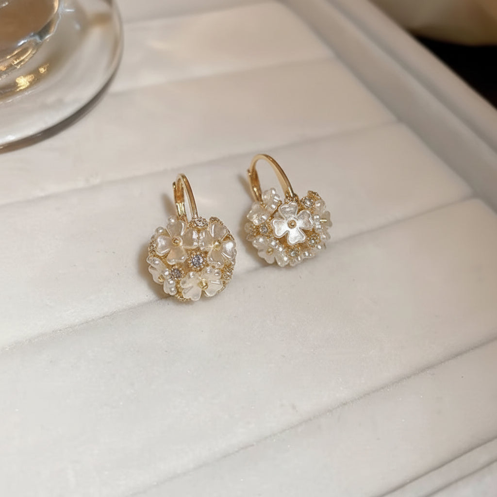 Pair of Gold Pearl Blossom Hoop Earrings with clear stones on a white surface
