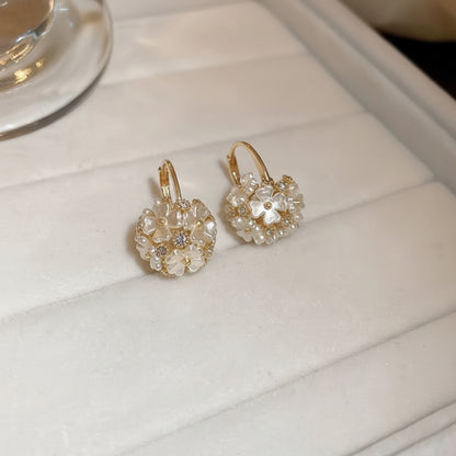 Pair of Gold Pearl Blossom Hoop Earrings with clear stones on a white surface