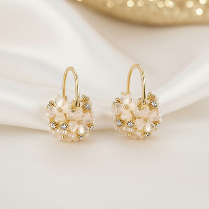 Pair of Gold Pearl Blossom Hoop Earrings with floral designs on a white background