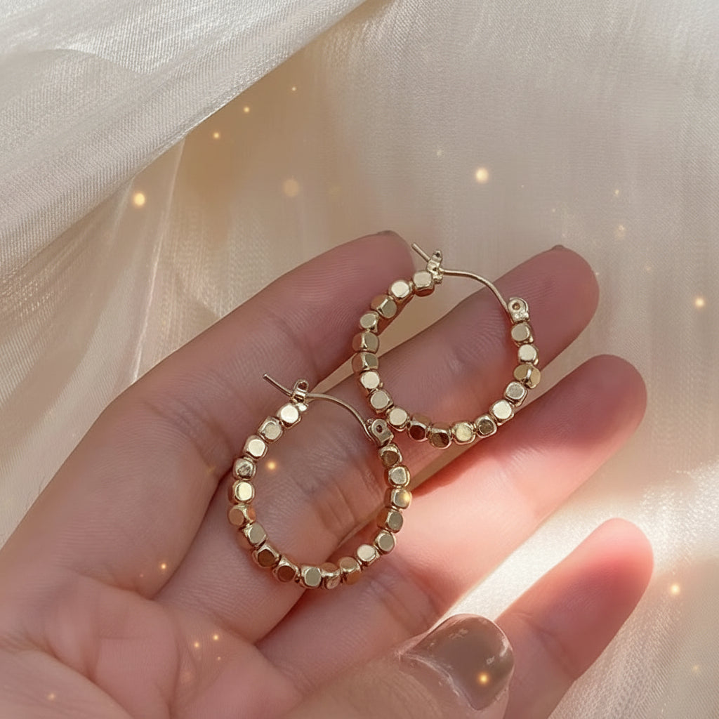 Gold Bead Accent Hoop Earrings held in a hand against a soft beige background