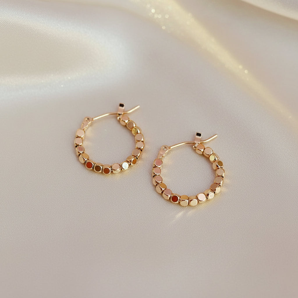 Gold Bead Accent Hoop Earrings with embedded stones on a soft pink background