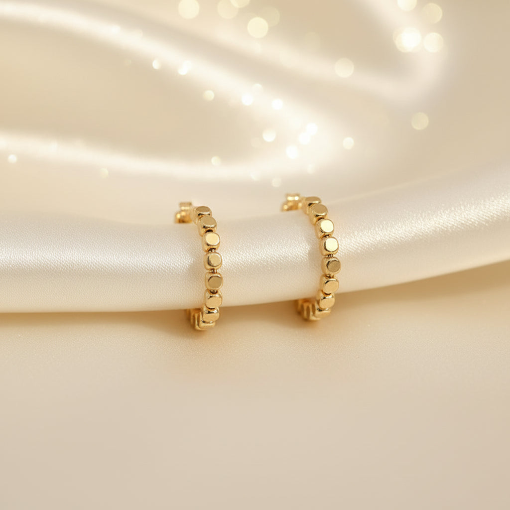 Gold Bead Accent Hoop Earrings on a beige fabric background