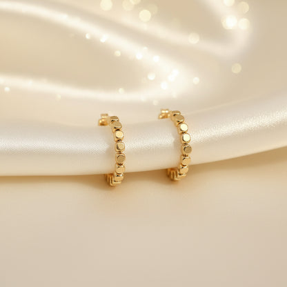 Gold Bead Accent Hoop Earrings on a beige fabric background