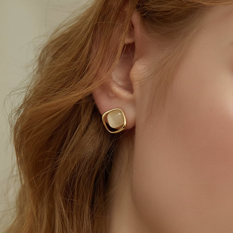 Close-up of a person wearing a Pearl Square Stud Earring with a light stone.