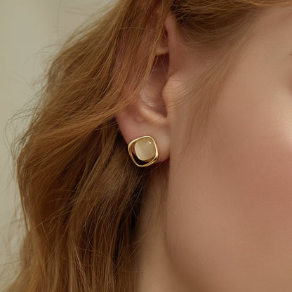 Close-up of a person wearing a Pearl Square Stud Earring with a light stone.