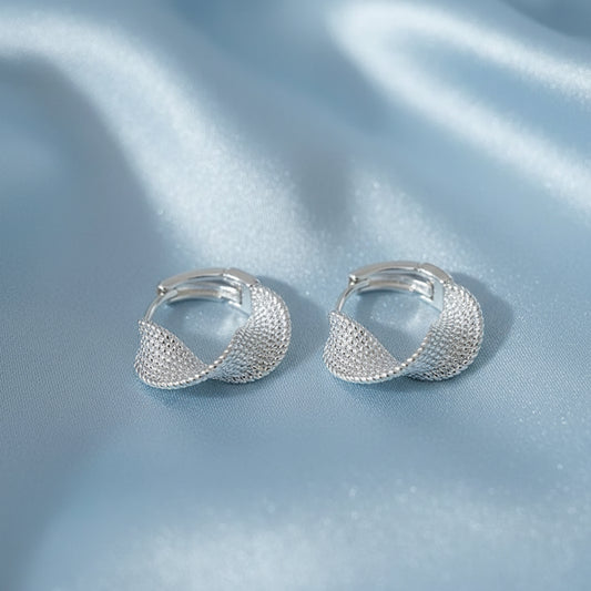 Silver Woven Twist Hoop Earrings on a beige fabric background with a card.