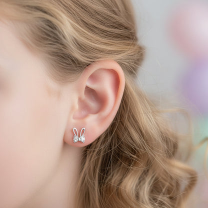 Close-up of an ear wearing a Silver Sparkle Bunny Bow Earring with a blurred background