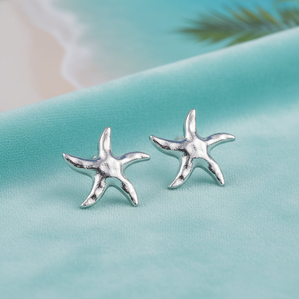 Silver Tide Starfish Earrings on a white surface with a blurred background