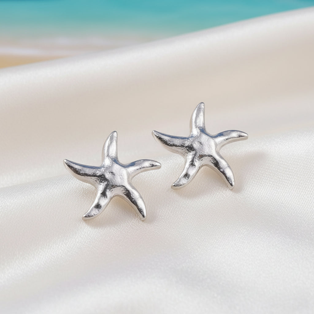 Silver Tide Starfish Earrings on a white surface with a blurred background