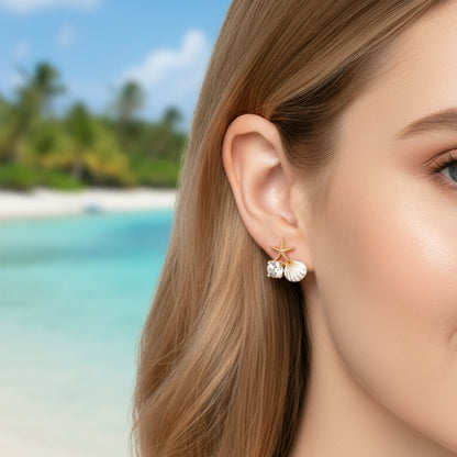 Close-up of a woman wearing Starfish Pearl & Crystal Earrings with a tropical beach background