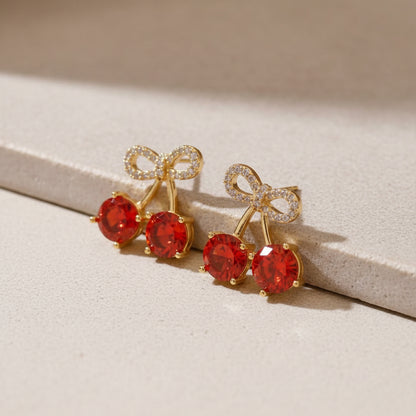Cherry bow pavé earrings with sparkling red gemstone detail and delicate feminine bow design on a soft elegant background