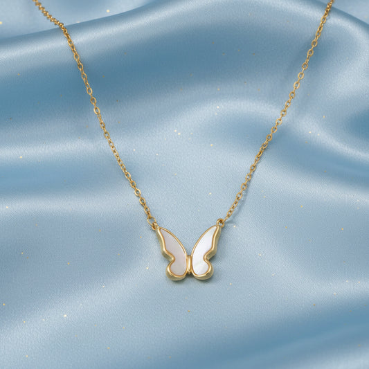 Close-up of the Shell Butterfly Necklace showing delicate mother of pearl inlay in a gold butterfly pendant on an adjustable chain, shown inside a jewelry box.