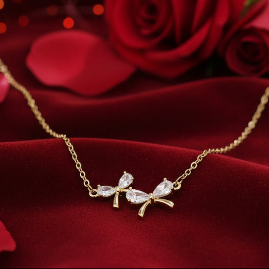 Gold Zircon Bow Necklace with diamond-like stones on a red fabric background