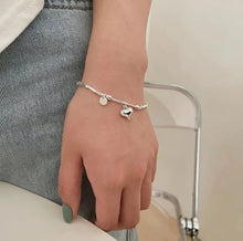 Load image into Gallery viewer, Heart Charm Bead Bracelet displayed on a wrist, showcasing its adjustable fit and refined style, girl with jeans.