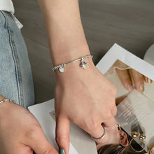 Load image into Gallery viewer, Heart Charm Bead Bracelet displayed on a wrist, showcasing its adjustable fit and refined style, girl with jeans reading magazine.