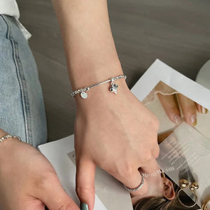 Heart Charm Bead Bracelet displayed on a wrist, showcasing its adjustable fit and refined style, girl with jeans reading magazine.