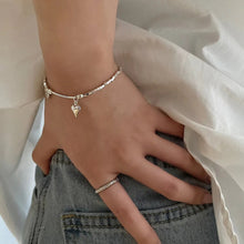 Load image into Gallery viewer, Heart Charm Bead Bracelet displayed on a wrist, showcasing its adjustable fit and refined style, jeans, hand on hip.