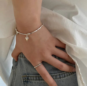 Heart Charm Bead Bracelet displayed on a wrist, showcasing its adjustable fit and refined style, jeans, hand on hip.