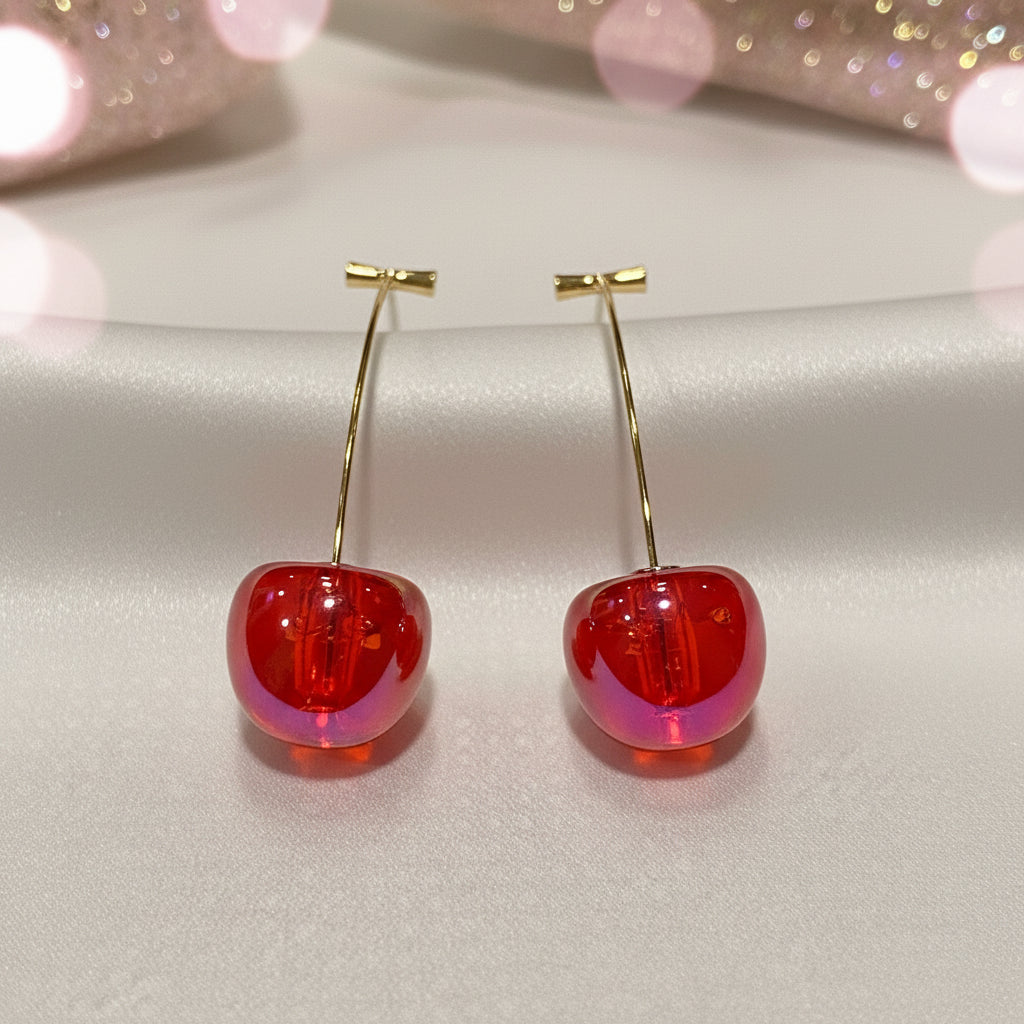 Iridescent Red Cherry Drop Earrings with gold hooks on a light pink background