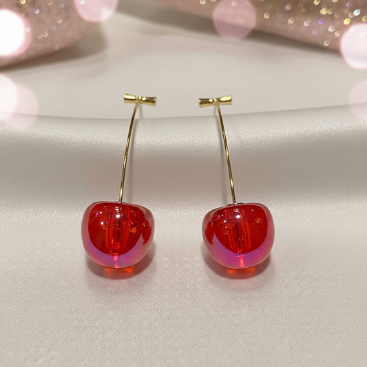 Iridescent Red Cherry Drop Earrings with gold hooks on a light pink background