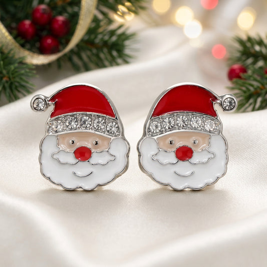 A pair of Jolly Santa Earrings with red enamel hats, white enamel beard, and clear rhinestone trim, set in silver-tone metal on a warm beige background.