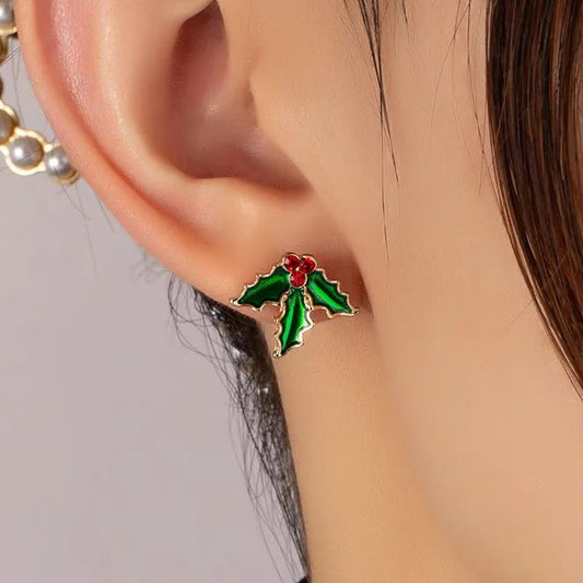 Close-up of an ear wearing a Red Berry Holly Earrings with a red berry on a neutral background